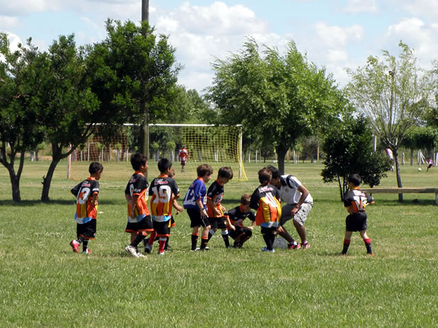 Chicos jugando al fútbol en la cancha del club